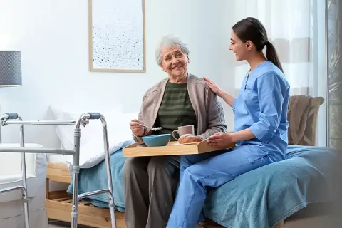 carer serving meal to elderly woman in hospice carer serving meal to elderly woman in hospice